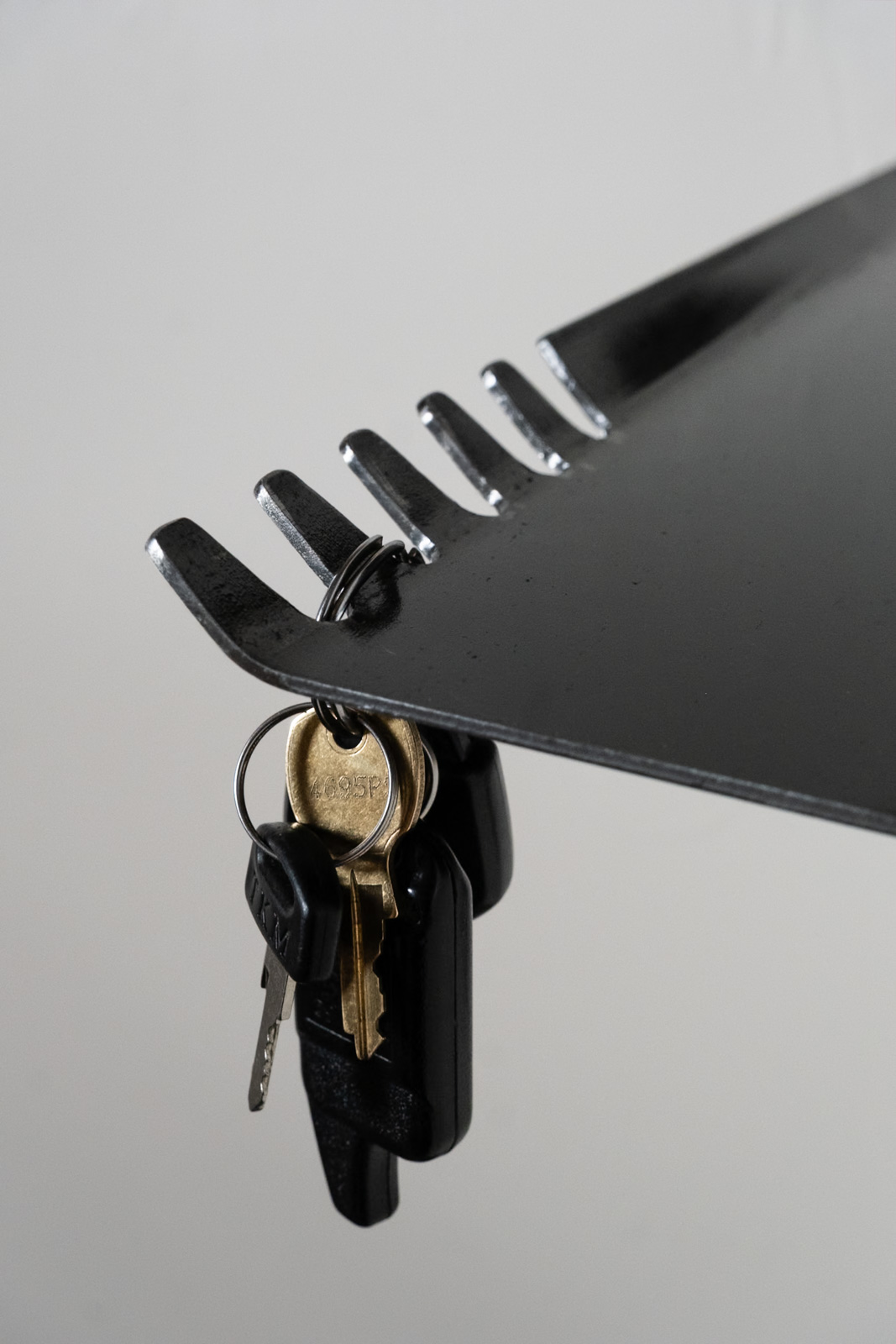 Close-up of minimalist steel key hooks and keys on the BND Series entryway organizer.